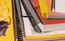 Vários livros encadernados com diferentes cores de espiral plástico